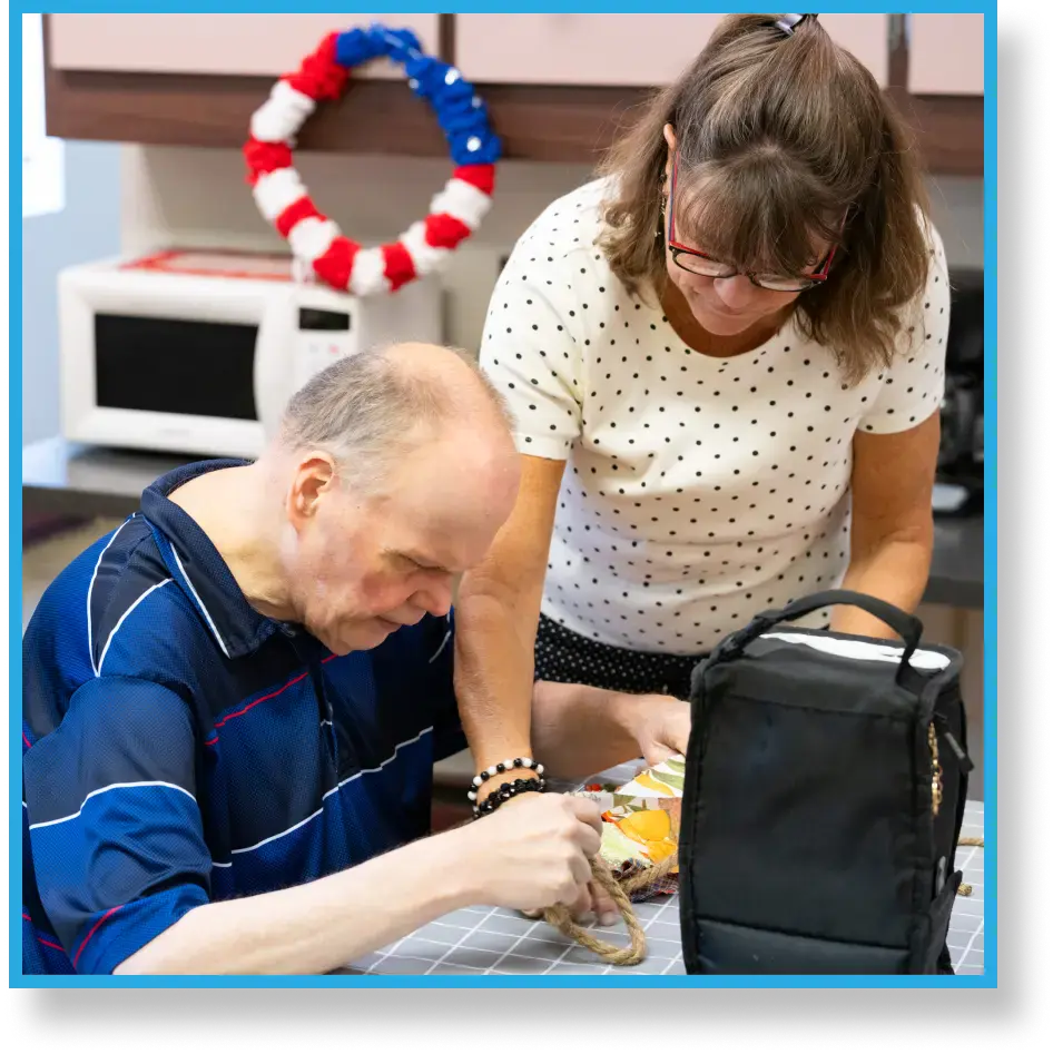 LBA staff member assisting client with a craft.